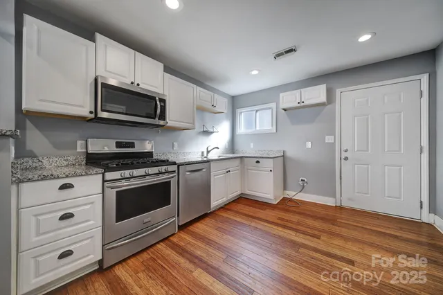 a kitchen with stainless steel appliances white cabinets a sink and a stove