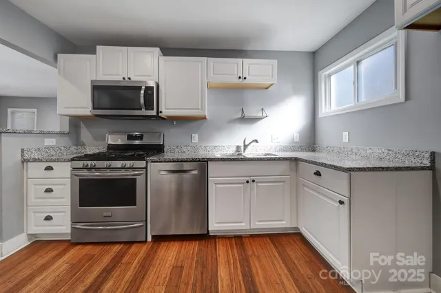 a kitchen with stainless steel appliances granite countertop a stove a sink and a microwave