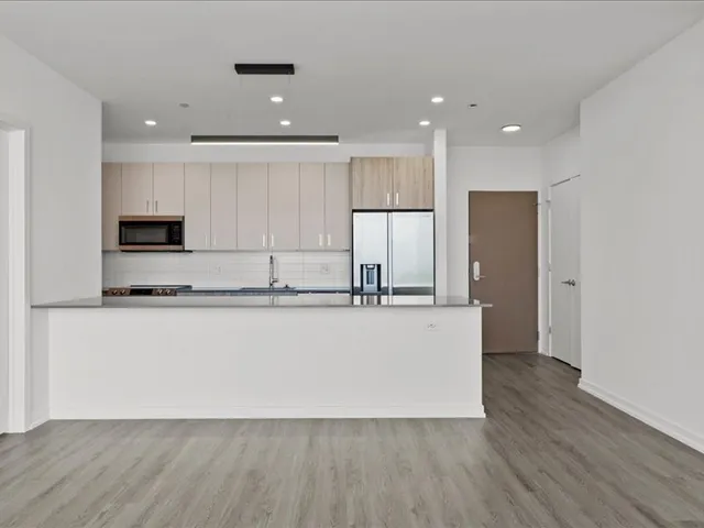 a large kitchen with stainless steel appliances granite countertop a stove a refrigerator a sink and a oven with wooden floor