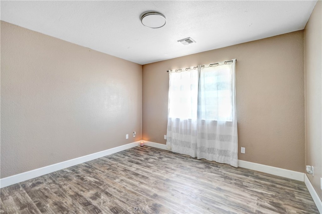 15395 Apache Road Apple Valley, CA 92307 - Photo 15 of 20 an empty room with wooden floor and windows
