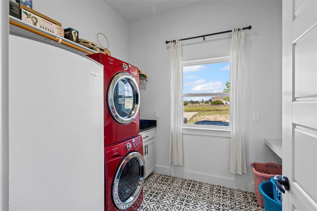 2045 Ellis Ridge Drive Weatherford, TX 76087 - Photo 13 of 40 Washroom featuring cabinet space, light tile patterned floors, stacked washing machine and dryer, and a water view