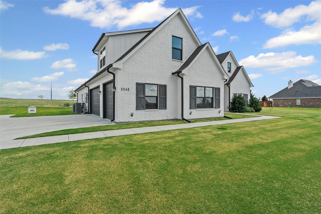2045 Ellis Ridge Drive Weatherford, TX 76087 - Photo 2 of 40 Modern style home featuring a front lawn, brick siding, driveway, a garage, and board and batten siding