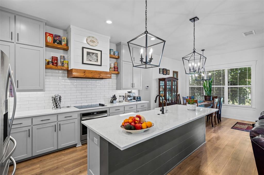 2045 Ellis Ridge Drive Weatherford, TX 76087 - Photo 9 of 40 Kitchen featuring granite counters, a kitchen island with sink, and light wood-style flooring