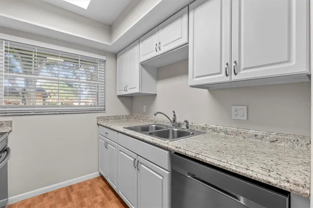 a kitchen with granite countertop stainless steel appliances white cabinets and a window