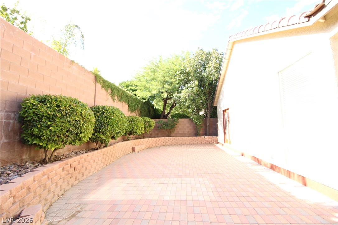 754 Rise Canyon Drive Henderson, NV 89052 - Photo 30 of 34 A private, paved courtyard offers serene outdoor living, bordered by verdant shrubs and sturdy block walls.