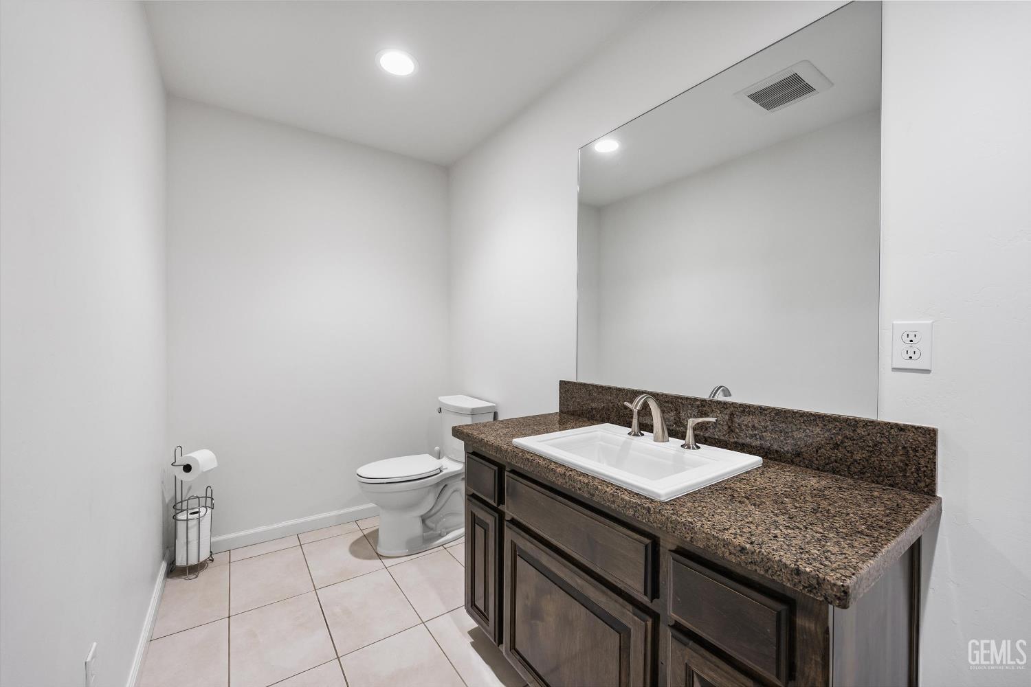 Undisclosed Address Bakersfield, CA 93314 - Photo 43 of 59 a bathroom with a granite countertop sink a toilet and a mirror