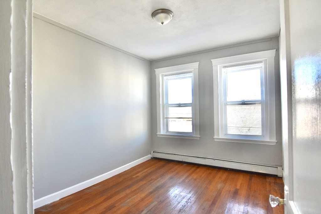 103 Homestead Street, Unit 1 Boston, MA 02121 - Photo 11 of 16 an empty room with wooden floor and windows