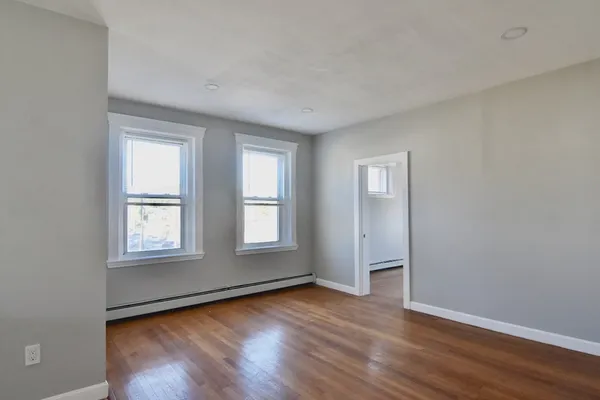 an empty room with wooden floor and windows