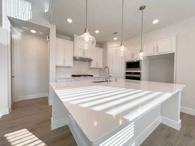 a large white kitchen with kitchen island a sink stainless steel appliances and a chandelier