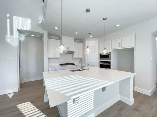 a large white kitchen with a refrigerator a sink and a wooden floor