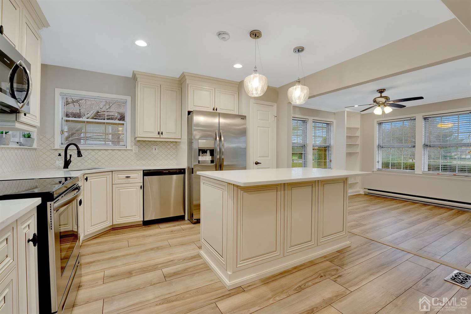 a large white kitchen with kitchen island a sink stainless steel appliances and cabinets