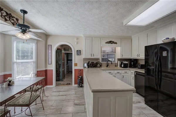 a kitchen with a refrigerator a stove a sink dishwasher with a dining table and chairs