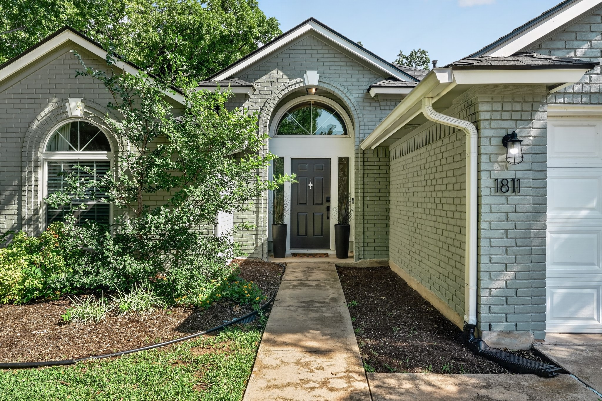 1811 Old Mill Road Cedar Park, TX 78613 - Photo 3 of 39 A welcoming brick facade with a prominent arched entry and lush landscaping creates appealing curb appeal.