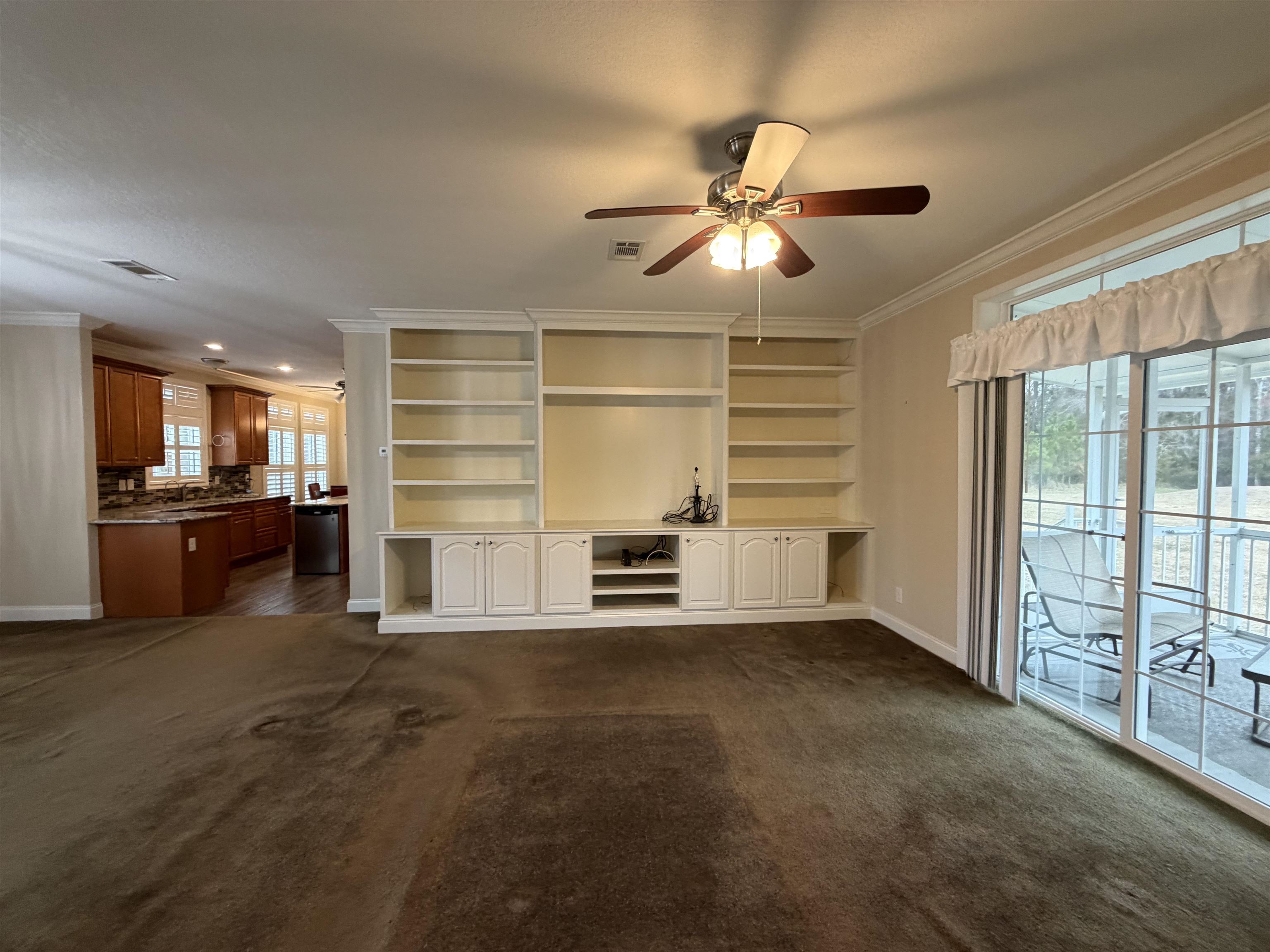 2434 Pellicer Road St. Augustine, FL 32092 - Photo 15 of 41 Unfurnished living room featuring ornamental molding, dark colored carpet, and a ceiling fan