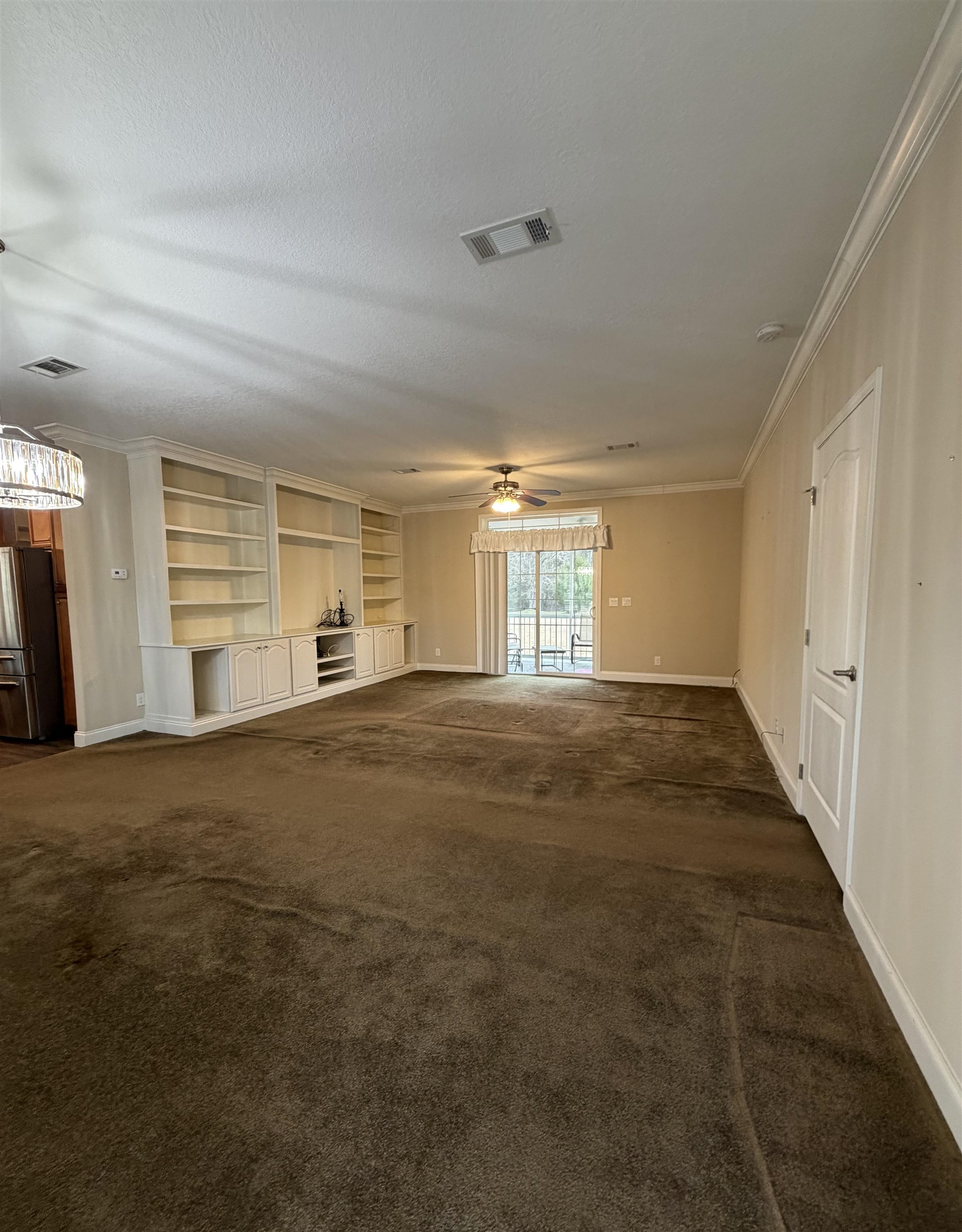 2434 Pellicer Road St. Augustine, FL 32092 - Photo 16 of 41 Unfurnished living room featuring ornamental molding, built in features, dark carpet, a ceiling fan, and a textured ceiling