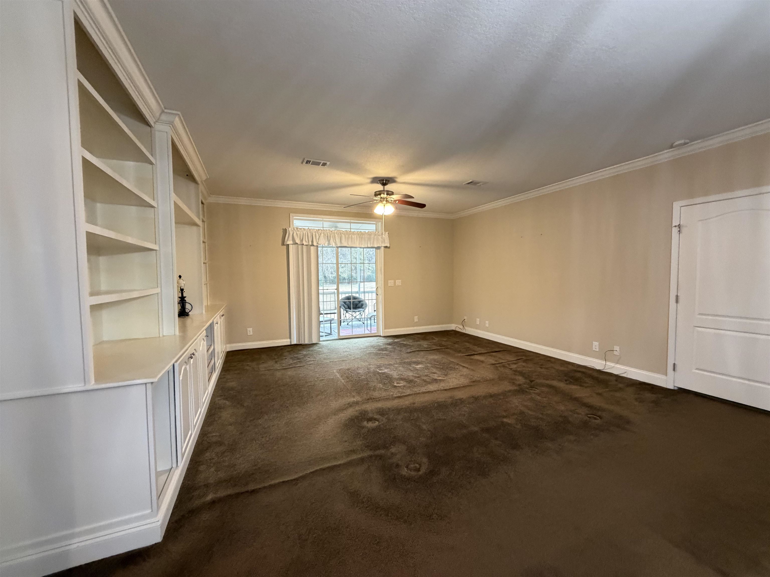2434 Pellicer Road St. Augustine, FL 32092 - Photo 17 of 41 Unfurnished living room with dark colored carpet, crown molding, and ceiling fan