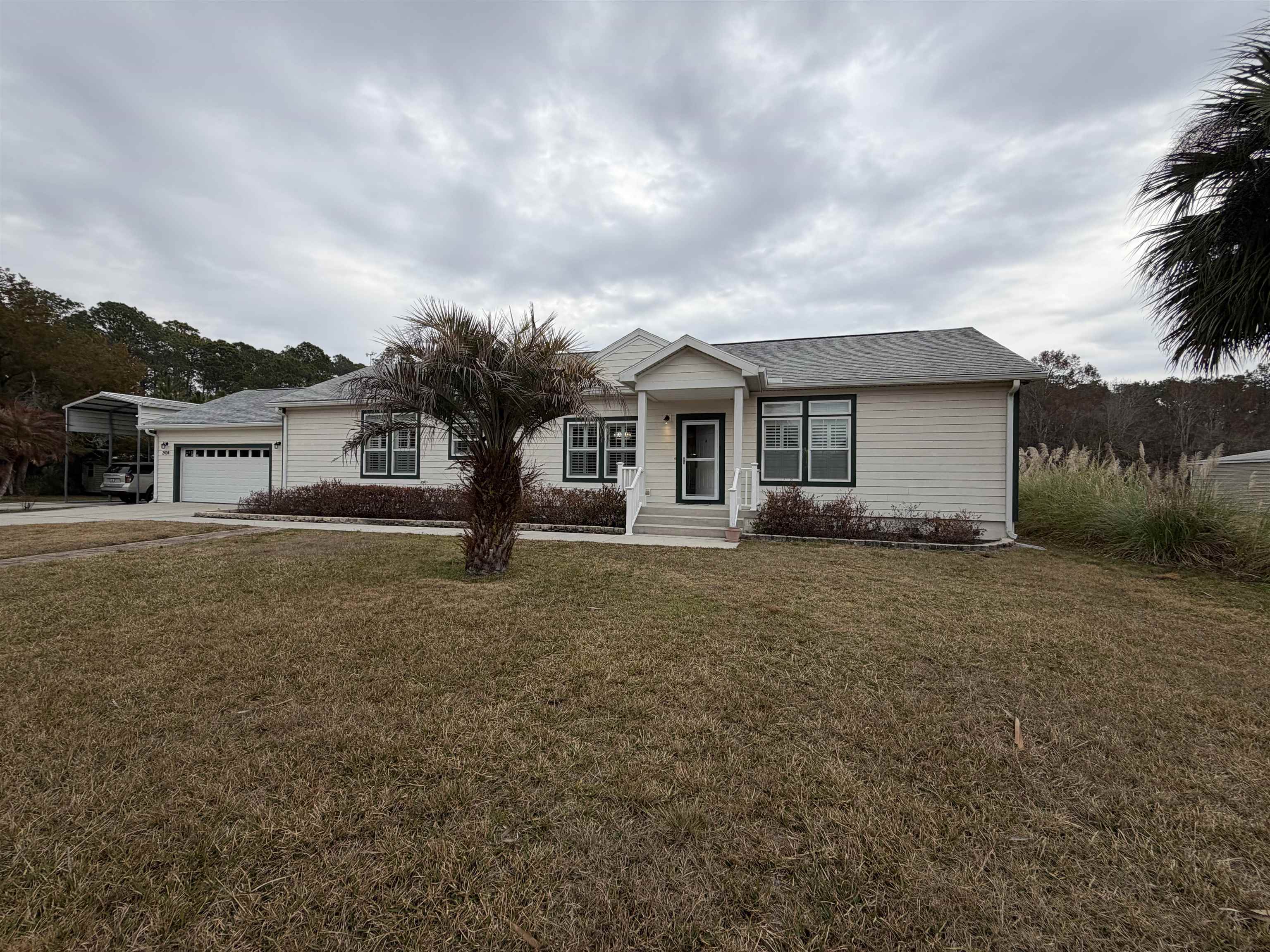 2434 Pellicer Road St. Augustine, FL 32092 - Photo 2 of 41 Ranch-style home featuring concrete driveway, a front lawn, a garage, a shingled roof, and a carport