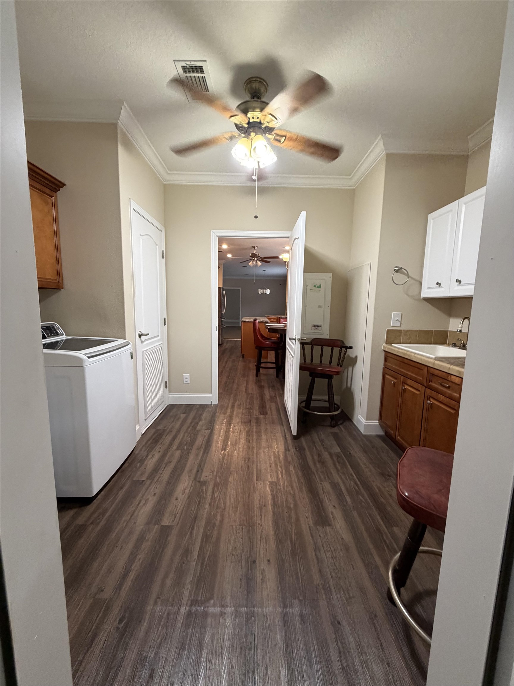 2434 Pellicer Road St. Augustine, FL 32092 - Photo 32 of 41 Kitchen with light countertops, dark wood-style flooring, ceiling fan, ornamental molding, and washer and clothes dryer