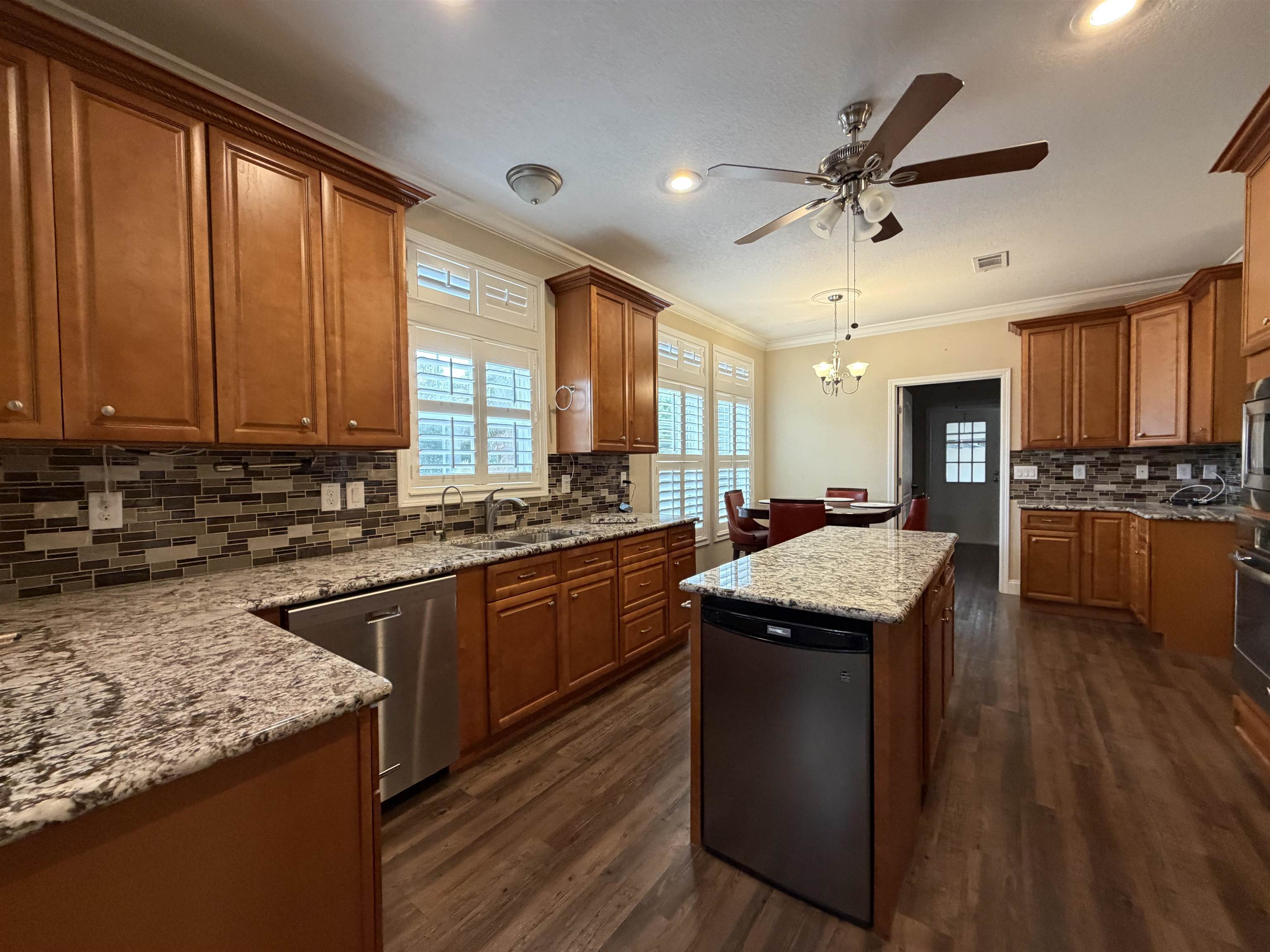 2434 Pellicer Road St. Augustine, FL 32092 - Photo 7 of 41 Kitchen with brown cabinetry, stainless steel appliances, backsplash, a center island, and ornamental molding