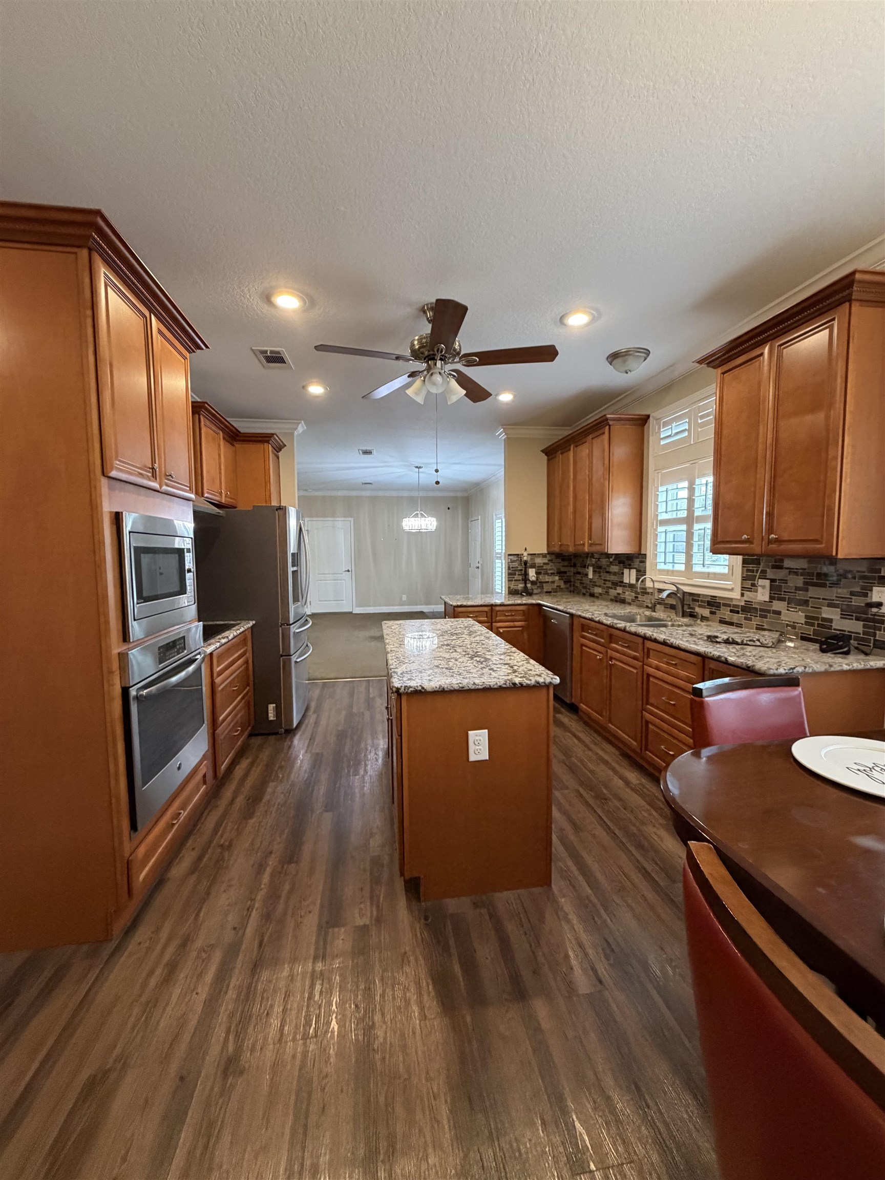 2434 Pellicer Road St. Augustine, FL 32092 - Photo 10 of 41 Kitchen with brown cabinetry, light stone counters, stainless steel appliances, a center island, and dark wood-style flooring
