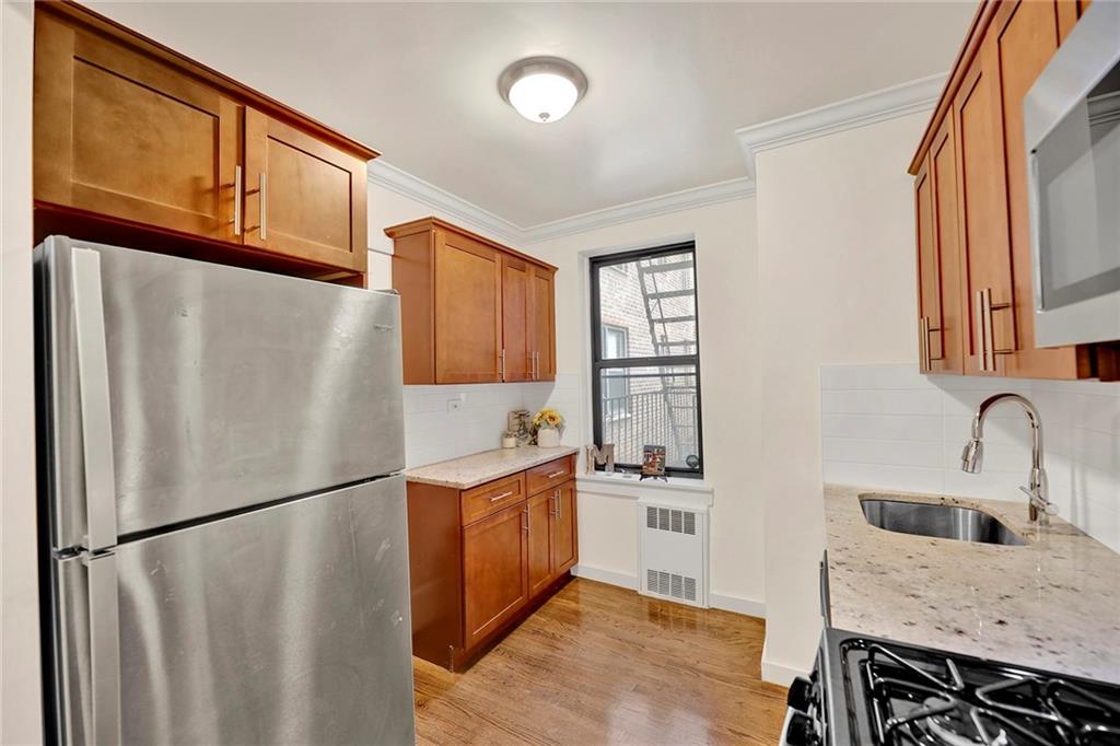 40 89th Street, Unit 4F Brooklyn, NY 11209 - Photo 11 of 22 a kitchen with stainless steel appliances granite countertop a refrigerator a sink dishwasher a stove with wooden cabinets next to a window