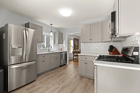 a kitchen with a refrigerator a stove a sink cabinets and wooden floor