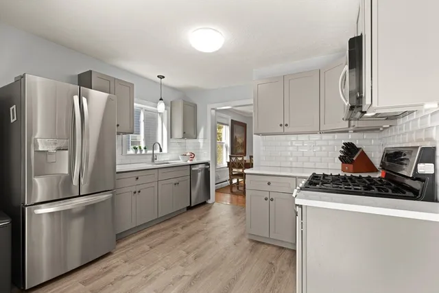 a kitchen with a refrigerator a stove a sink cabinets and wooden floor