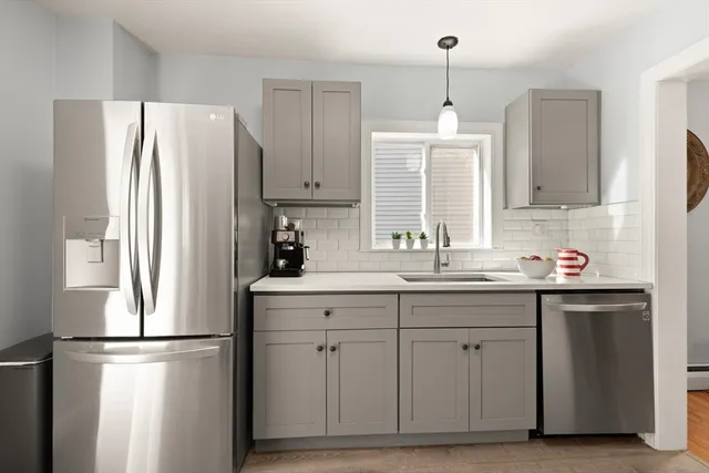 a kitchen with refrigerator a sink cabinets and wooden floor