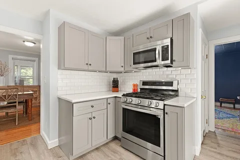 a kitchen with cabinets stainless steel appliances and wooden floor