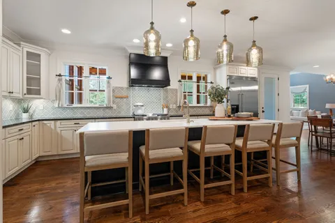 a dining room with wooden floor a chandelier a wooden table and chairs