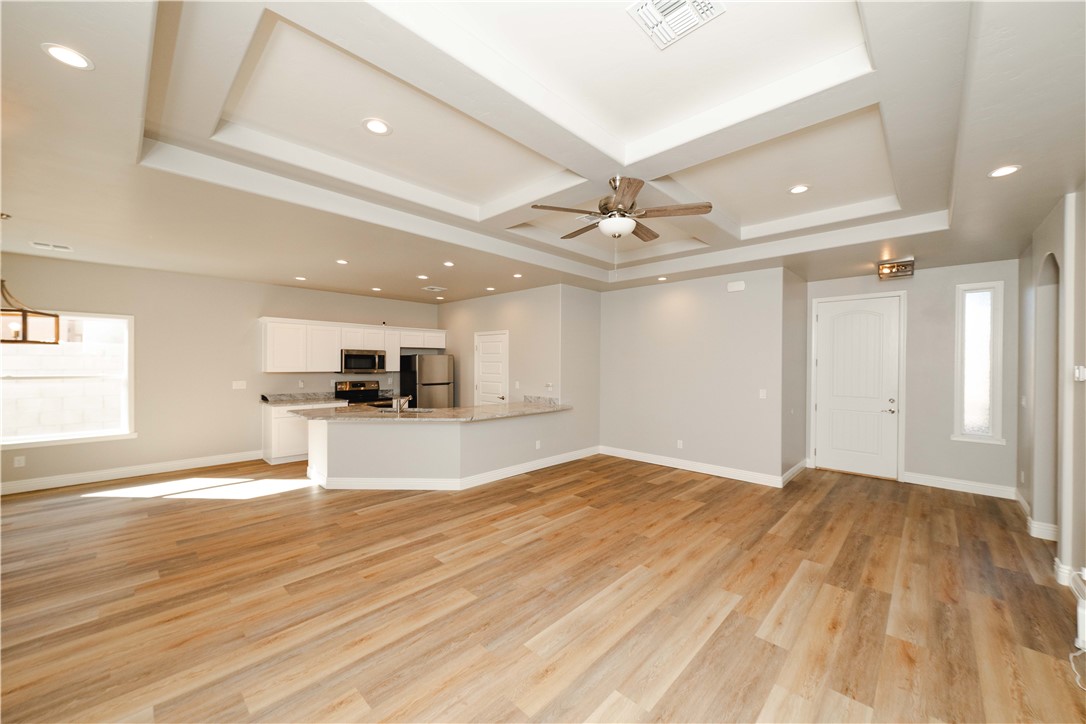 3640 North Kenneth Road Kingman, AZ 86409 - Photo 15 of 44 Unfurnished living room with plenty of natural light, recessed lighting, a ceiling fan, light wood-style floors, and coffered ceiling