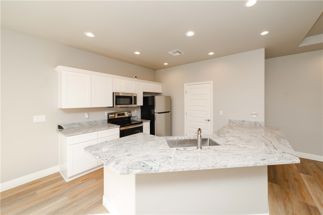 3640 North Kenneth Road Kingman, AZ 86409 - Photo 17 of 44 Kitchen with white cabinets, a peninsula, appliances with stainless steel finishes, recessed lighting, and light stone counters