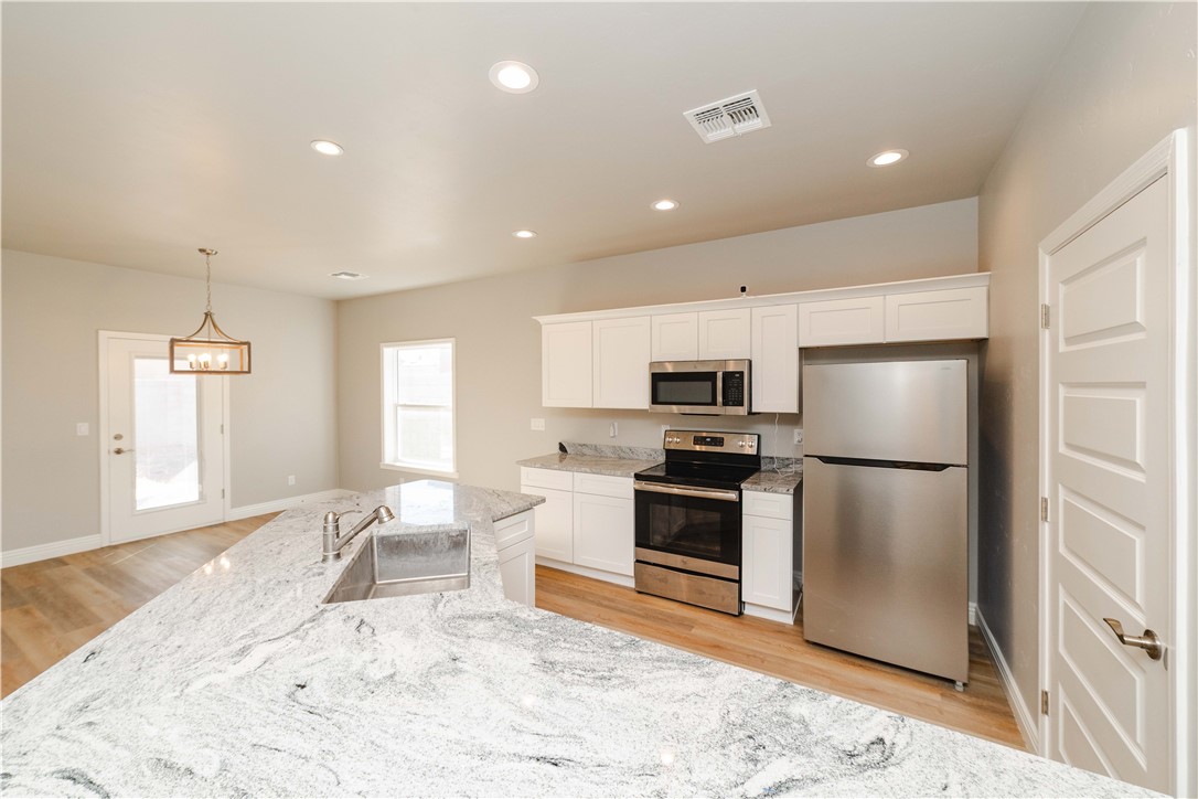 3640 North Kenneth Road Kingman, AZ 86409 - Photo 18 of 44 Kitchen with stainless steel appliances, recessed lighting, white cabinets, pendant lighting, and light stone counters
