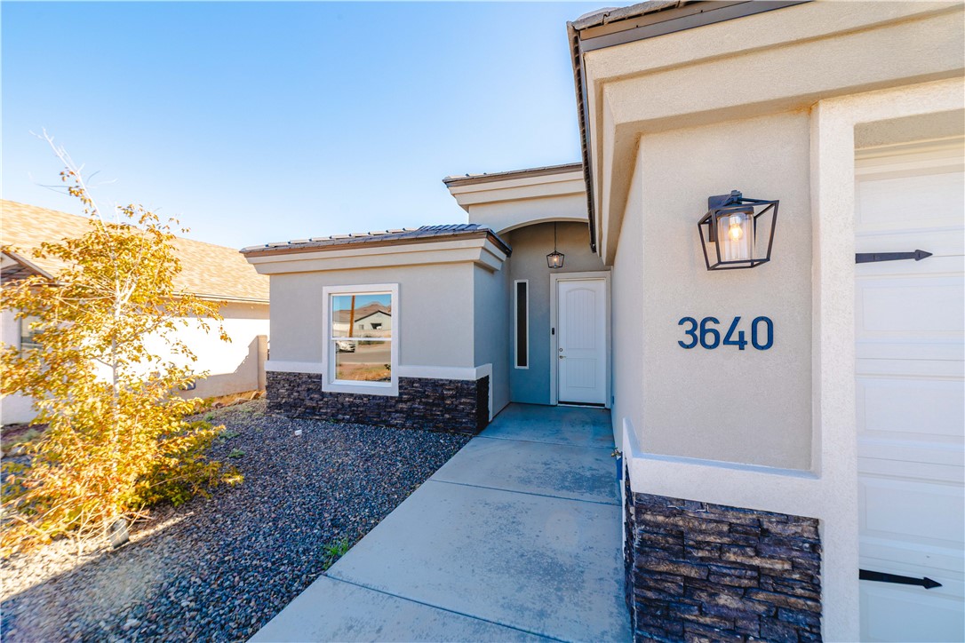 3640 North Kenneth Road Kingman, AZ 86409 - Photo 2 of 44 Property entrance with stone siding, stucco siding, a tile roof, and a garage