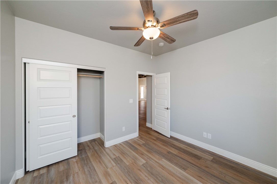 3640 North Kenneth Road Kingman, AZ 86409 - Photo 8 of 44 Unfurnished bedroom with wood finished floors, a closet, and a ceiling fan