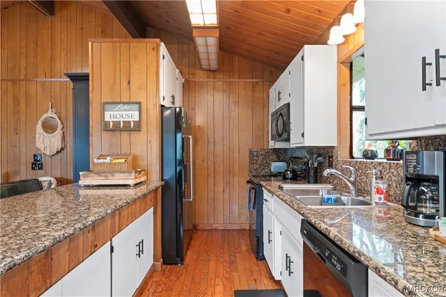 a kitchen with stainless steel appliances granite countertop a sink a stove and a wooden cabinets