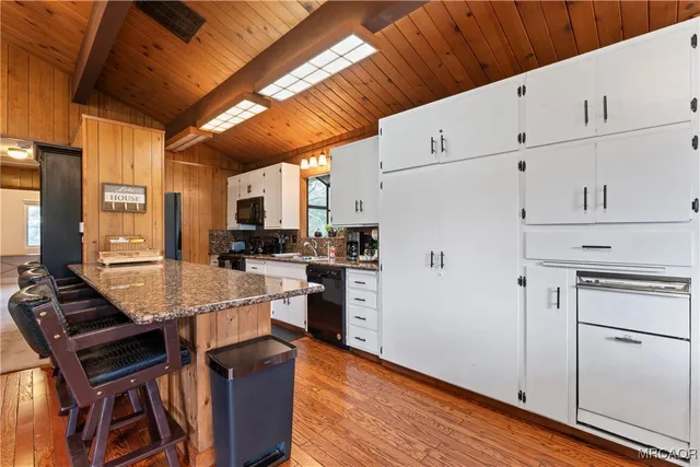 a kitchen with stainless steel appliances granite countertop a stove a refrigerator a sink dishwasher and white countertops with wooden floor