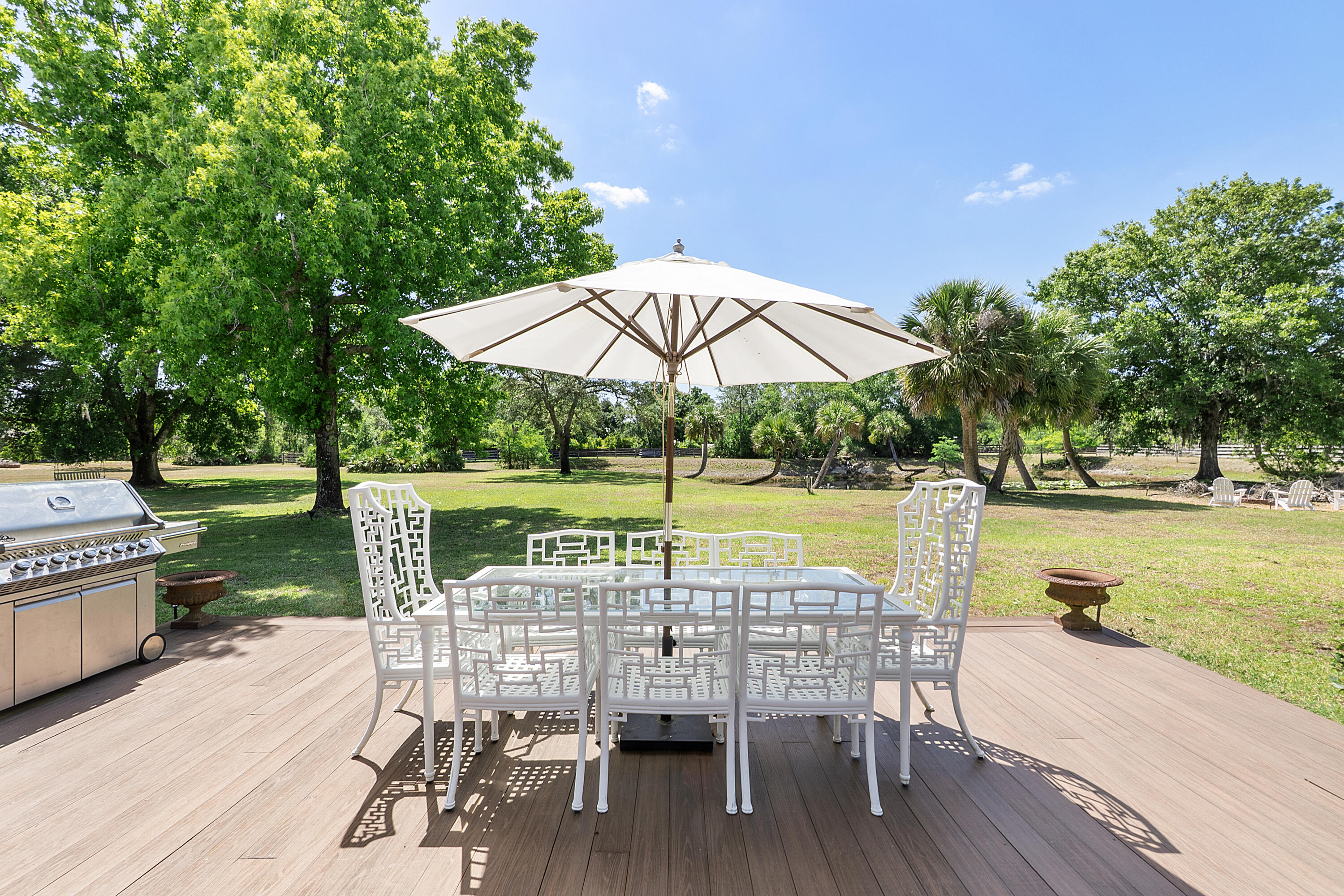 32801 Highway 441, Unit 64 Okeechobee, FL 34972 - Photo 31 of 138 a view of a lake with table and chairs under an umbrella with wooden floor and fence