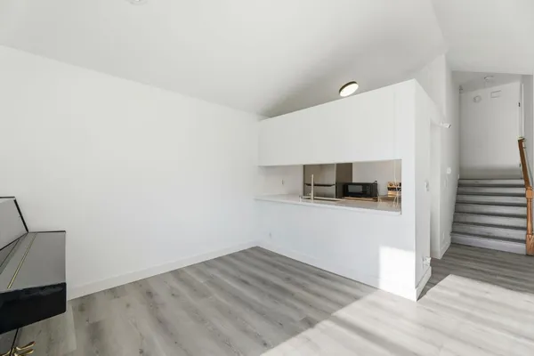 a view of a livingroom with wooden floor and a hallway