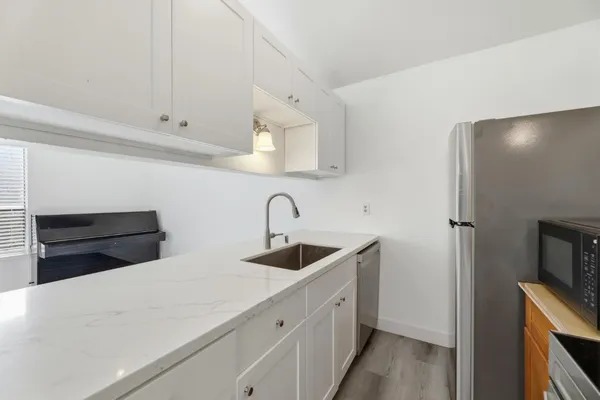 a kitchen with white cabinets and sink