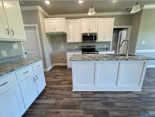 a kitchen with stainless steel appliances granite countertop a sink a stove a microwave a counter space and cabinets