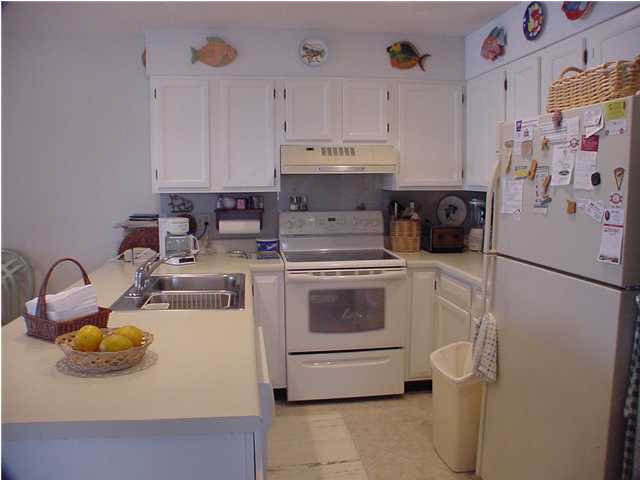 6015 Highway Santa Rosa Beach, Unit A101 30A Santa Rosa Beach, FL 32459 - Photo 4 of 18 a kitchen with a refrigerator a stove a microwave and cabinets