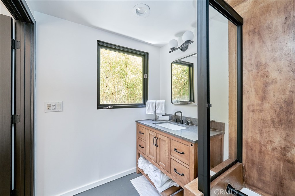 8457 Ridpath Drive Los Angeles, CA 90046 - Photo 14 of 33 a bathroom with a granite countertop sink a mirror and a window