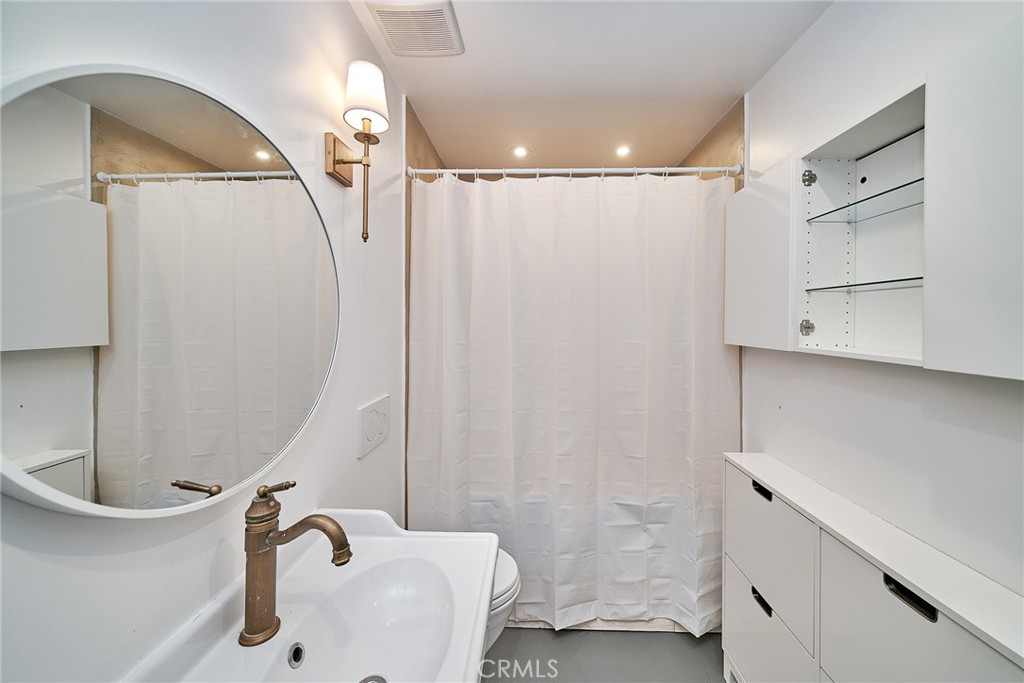 8457 Ridpath Drive Los Angeles, CA 90046 - Photo 26 of 33 a bathroom with a sink a glass door shower and a mirror