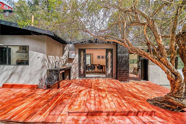 front view of a house with large trees and wooden fence