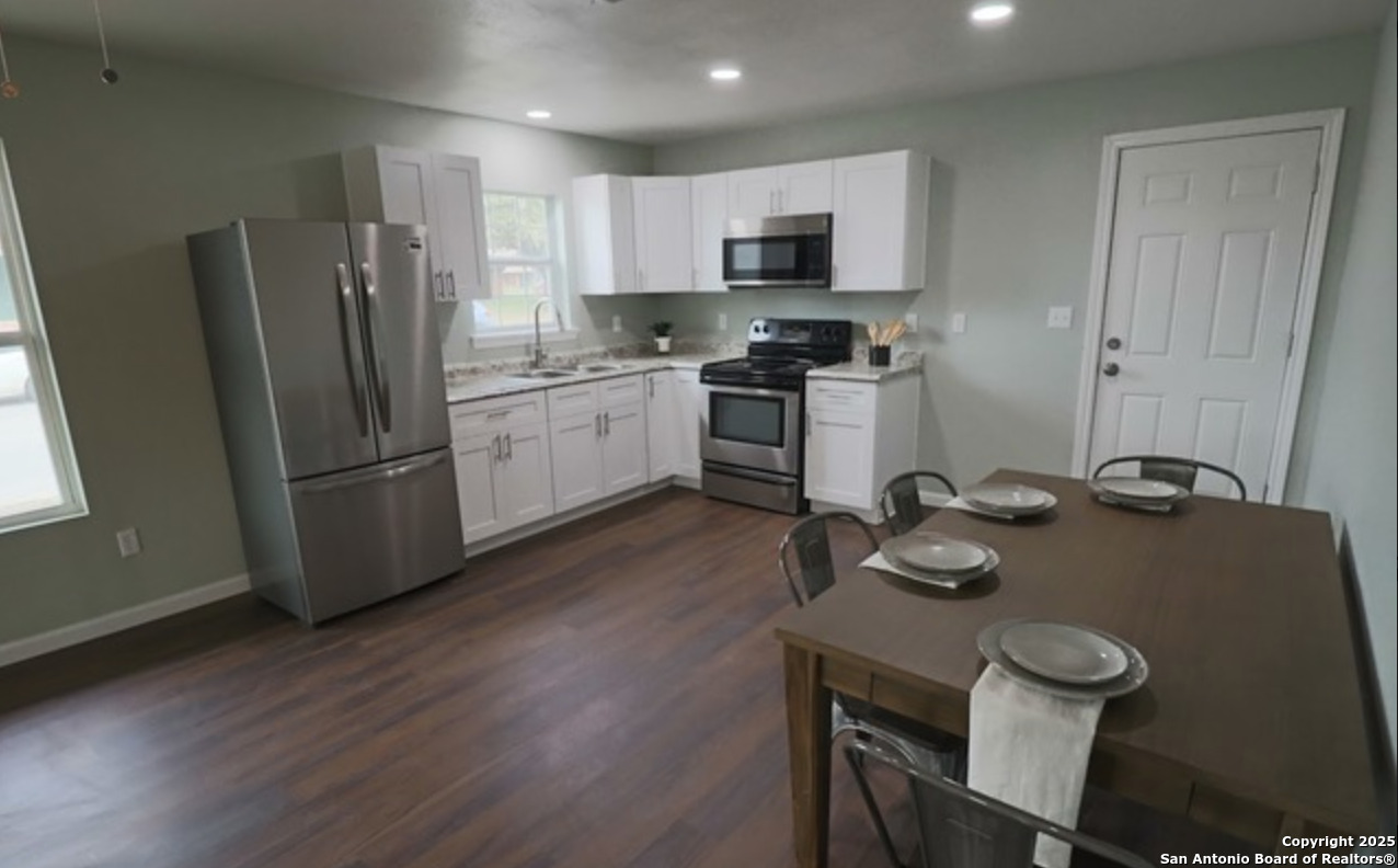 433 West Adams Street Pleasanton, TX 78064 - Photo 3 of 13 a kitchen with a sink a stove a refrigerator and chairs
