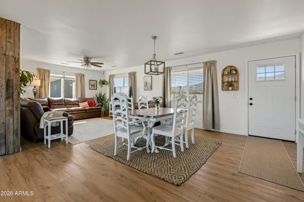 a kitchen with stainless steel appliances kitchen island granite countertop a refrigerator a stove a dining table and chairs with wooden floor