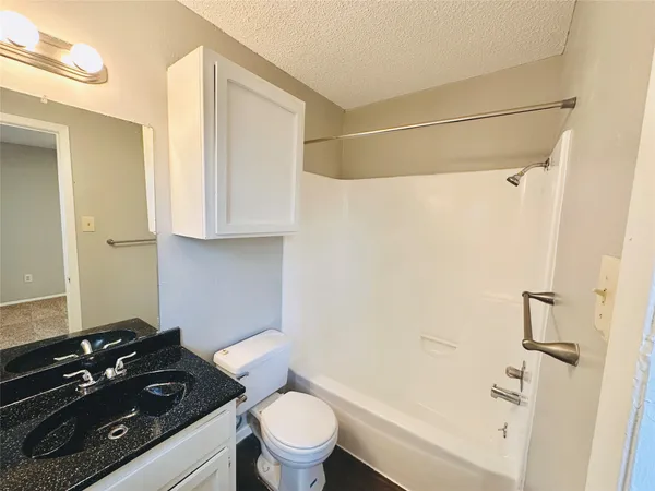 a bathroom with a granite countertop sink toilet and shower
