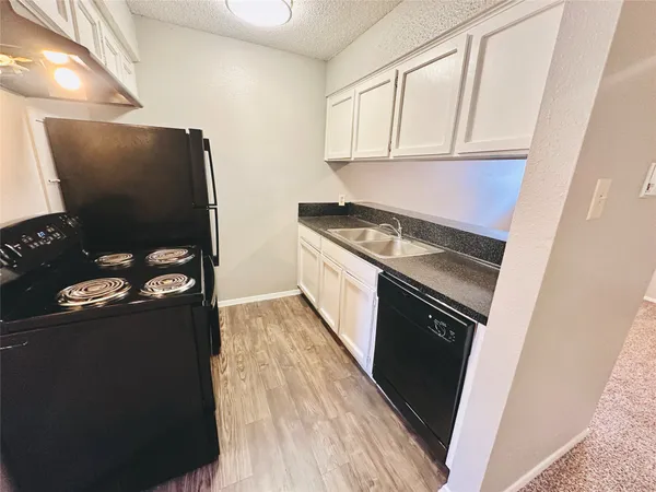 a kitchen with granite countertop white cabinets and black appliances