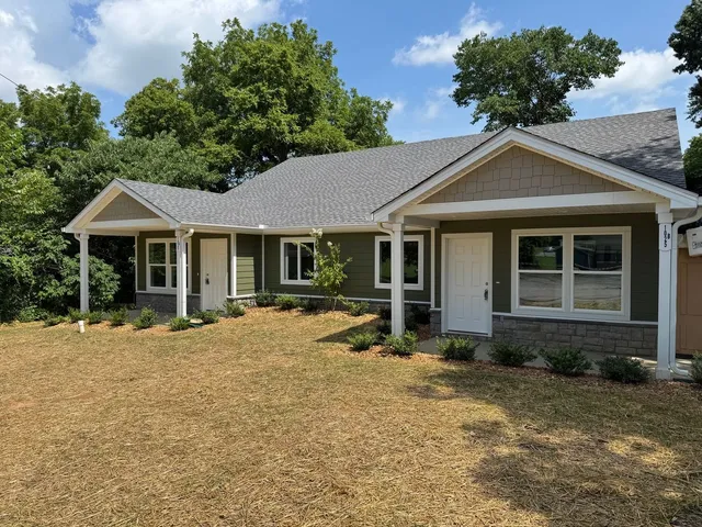a view of a house with a yard and large tree